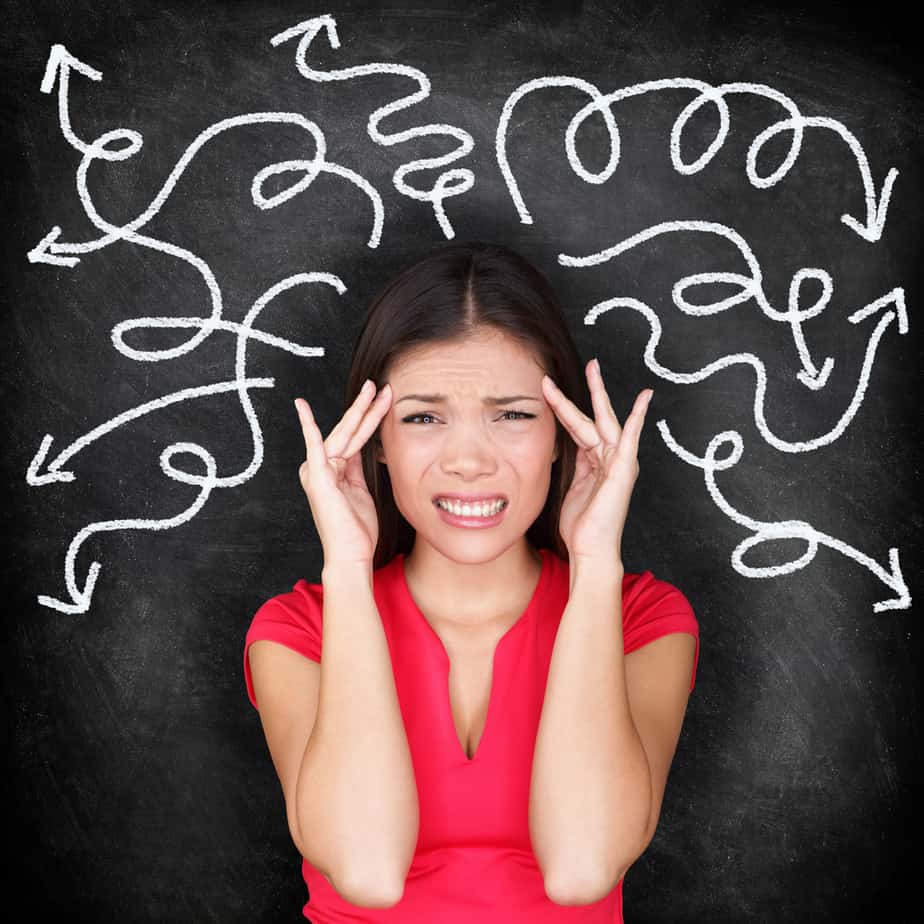 Confused woman - people feeling confusion and chaos. Indecisive, disorientated and bewildered woman stressed with headache over decision making. Girl in 20s on blackboard background. Asian / Caucasian